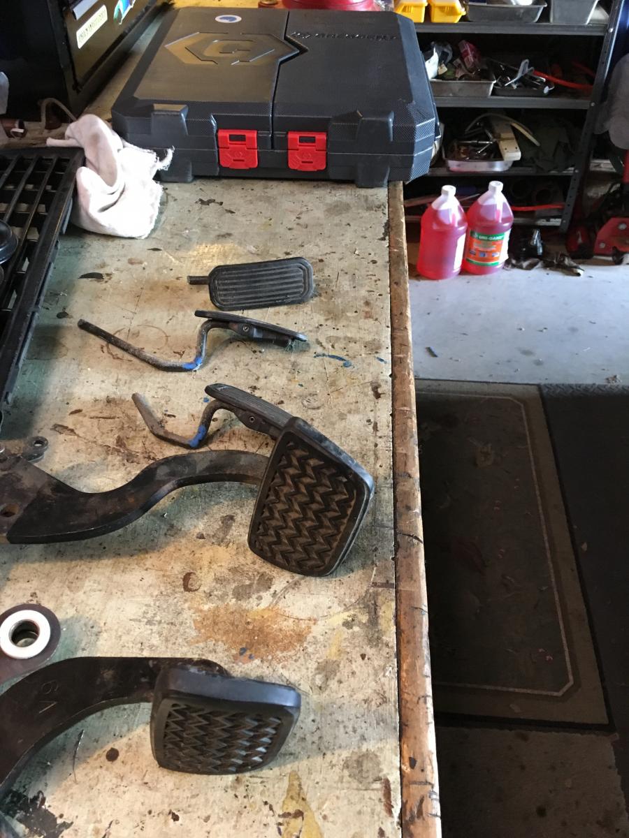 Pedals gathered from our second junkyard trip arranged on a workbench
