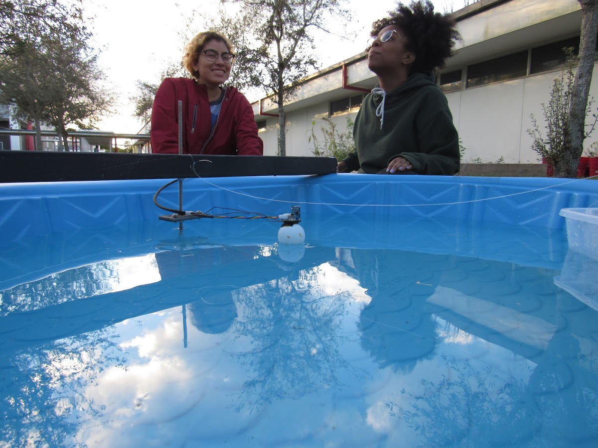 Two engineering members smiling alongside the experiment.